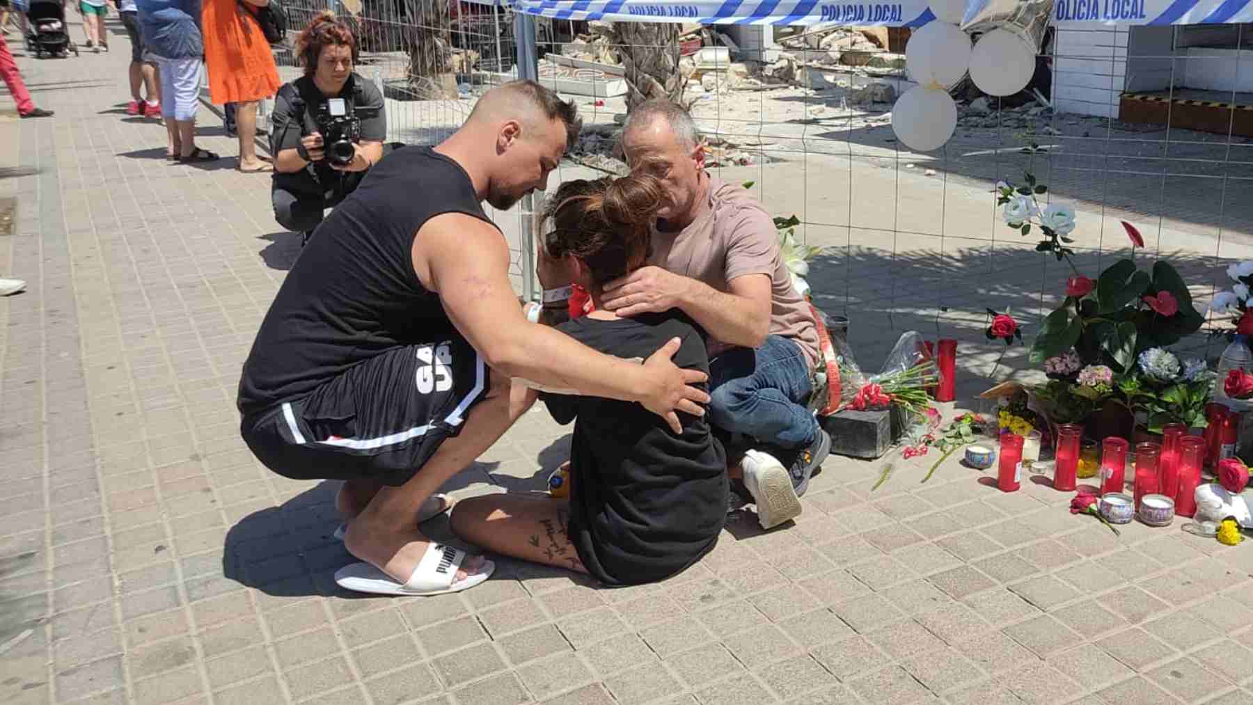 La joven pareja de turistas alemanes tras depositar un ramo de frente frente al Medusa Beach en Playa de Palma.