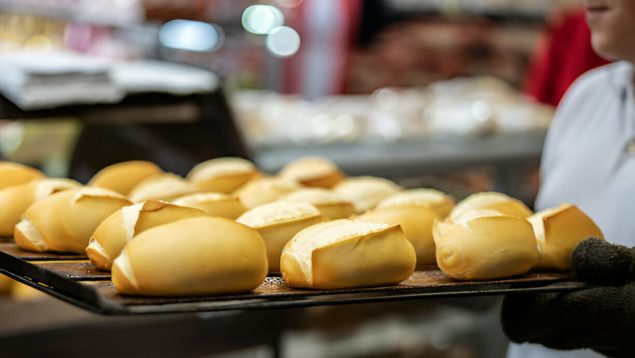 Un panadero lleva una bandeja de panecillos.