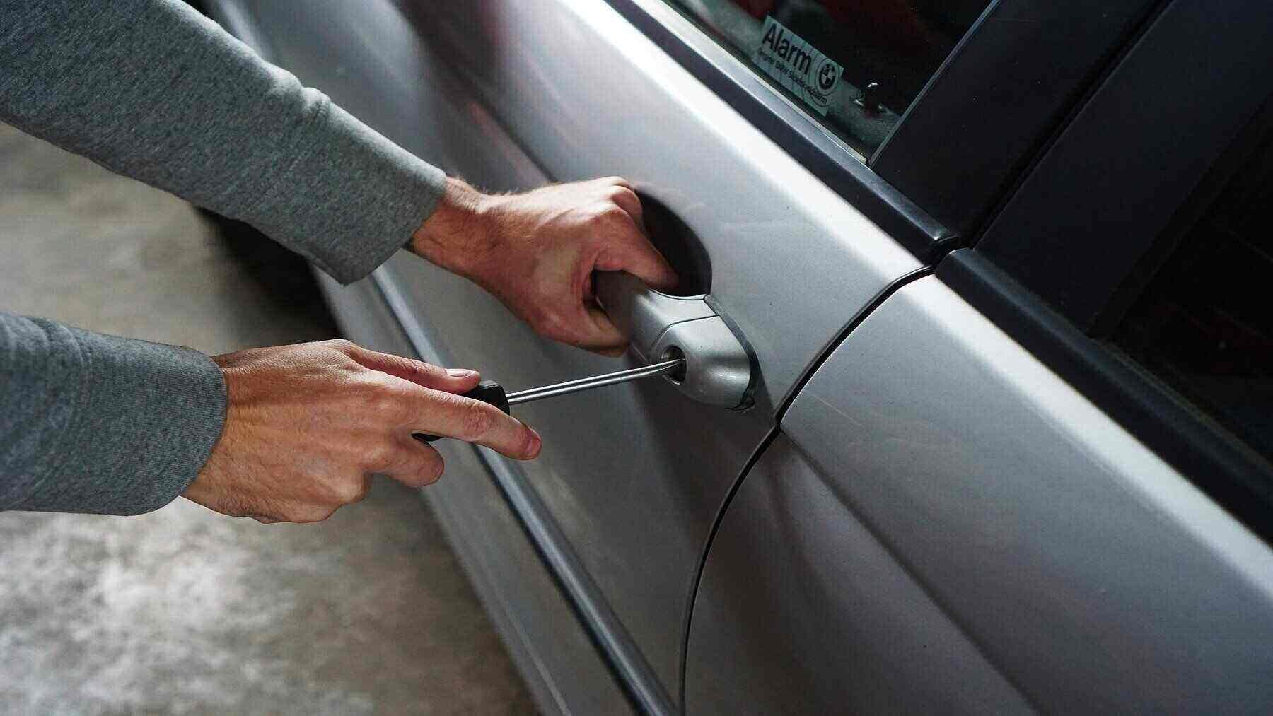 Ladrón robando un coche gris metalizado.