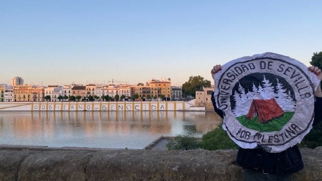 Un estudiante de la Universidad de Sevilla posa junto a la pintada.