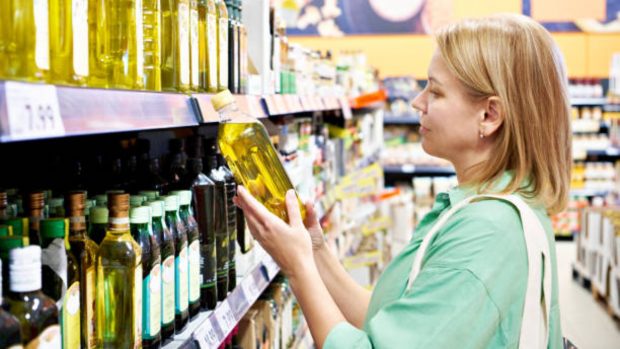 Mujer compra aceite de oliva en un supermercado.