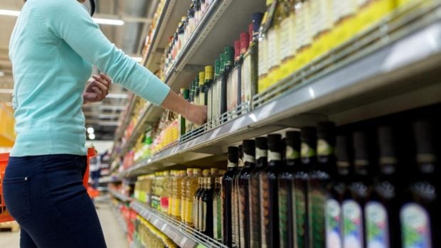 Mujer compra una botella de aceite de oliva en un supermercado.
