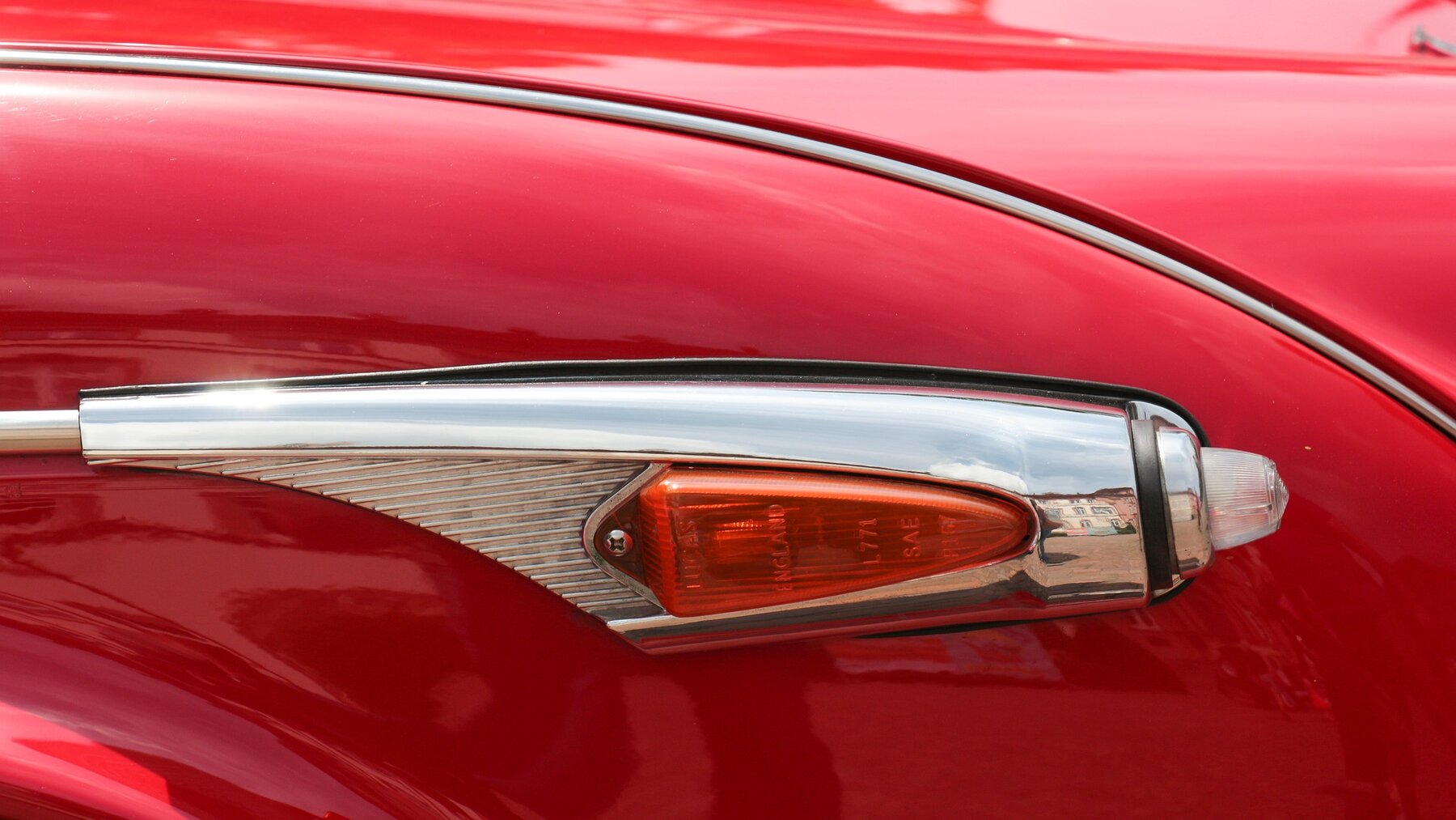 Uno de los intermitentes naranjas de un coche clásico rojo.