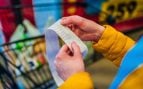 Manos de mujer sostienen ticket de compra en un supermercado.