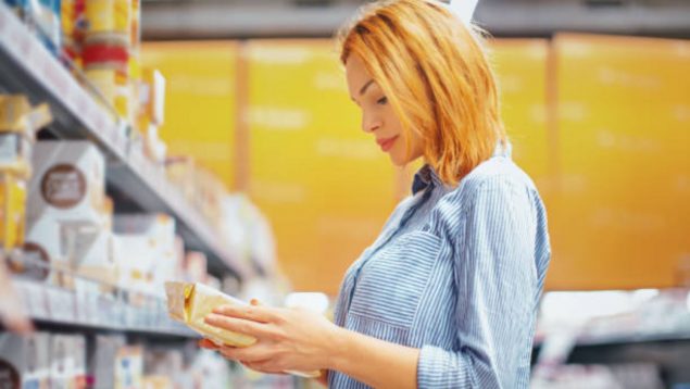 mujer mirando un paquete de café en un supermercado.