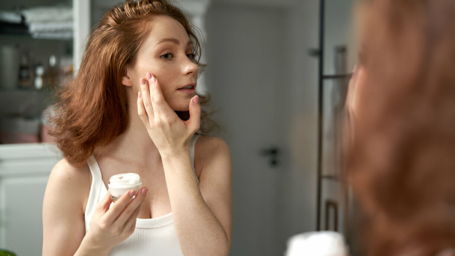 Mujer aplicándose crema facial.