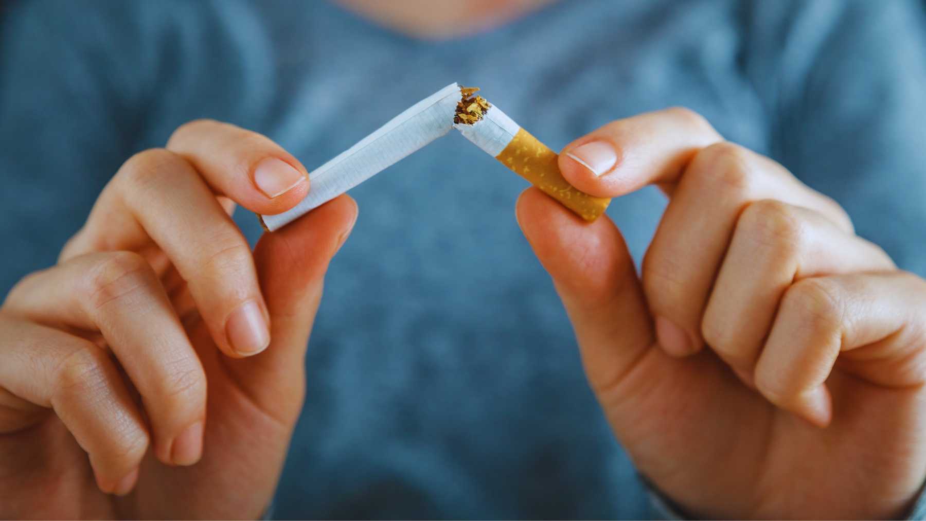 Una mujer rompiendo un cigarrillo.