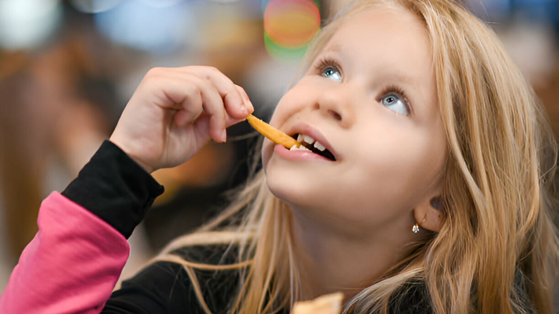 Niña comiendo patatas fritas.