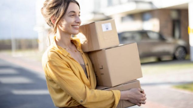 Foto de una mujer que sonríe mientras lleva tres paquetes.