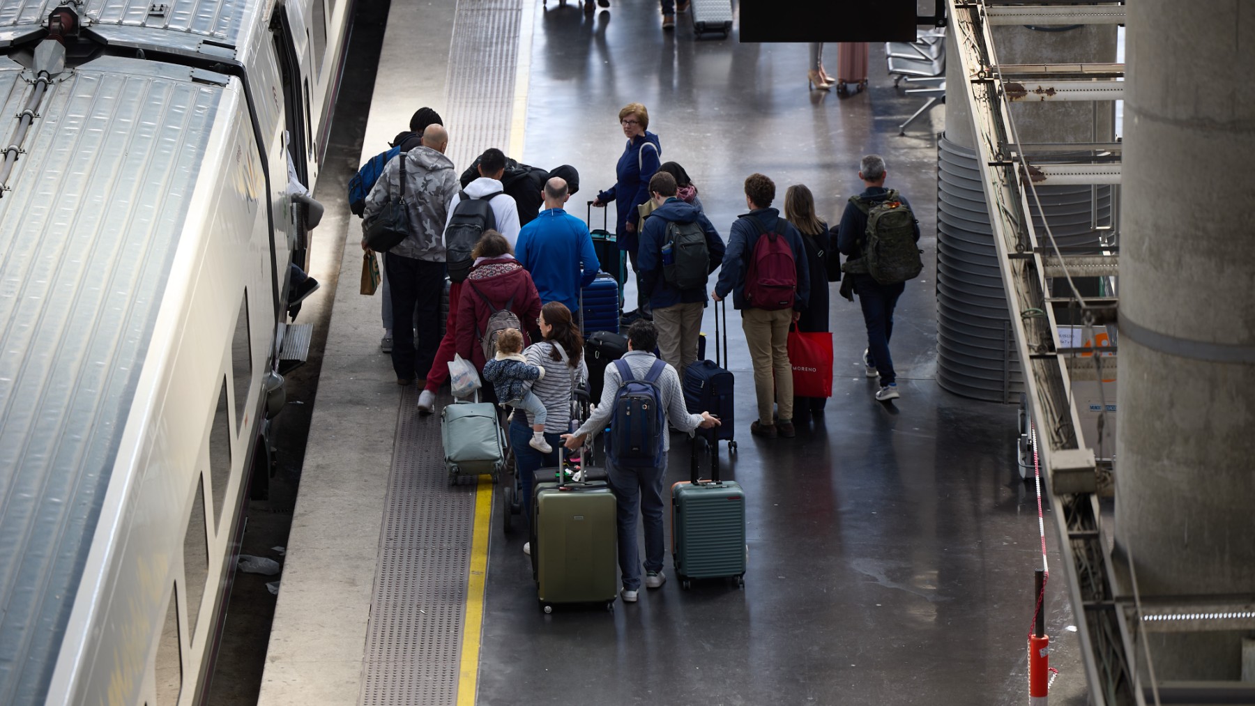 Varias personas esperan a un tren en un andén. (EP)