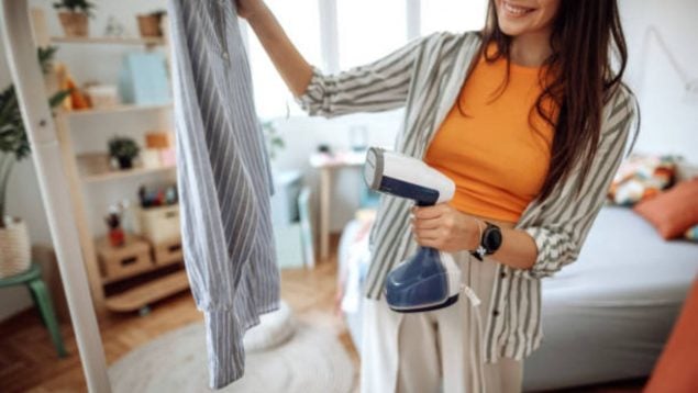 Foto de una mujer que está planchando una camisa con una plancha vertical.