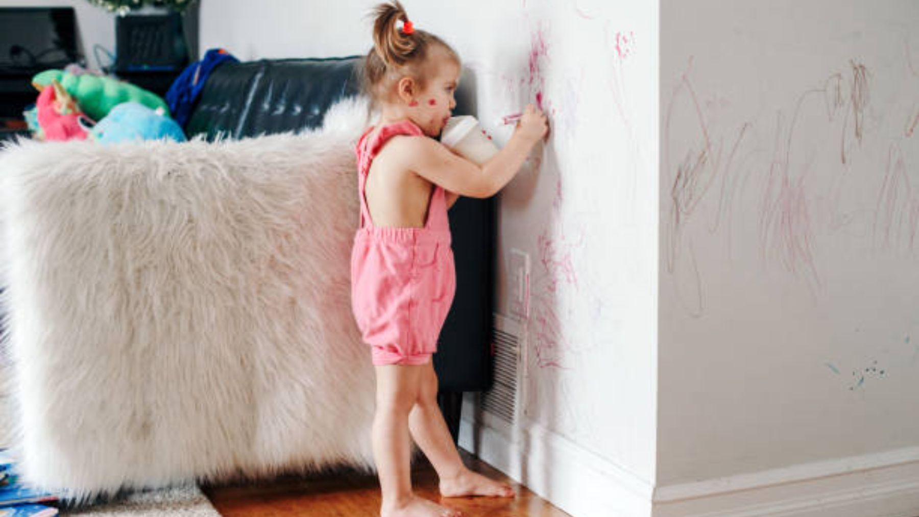 Niña pintando la pared de casa.