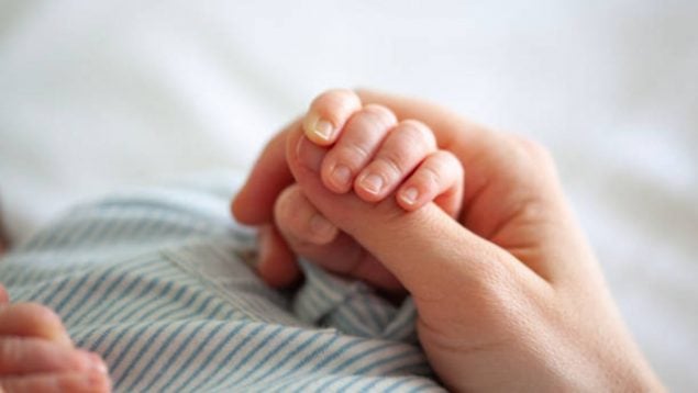 Foto de la mano de un bebé recién nacido que se coge al dedo de su madre.