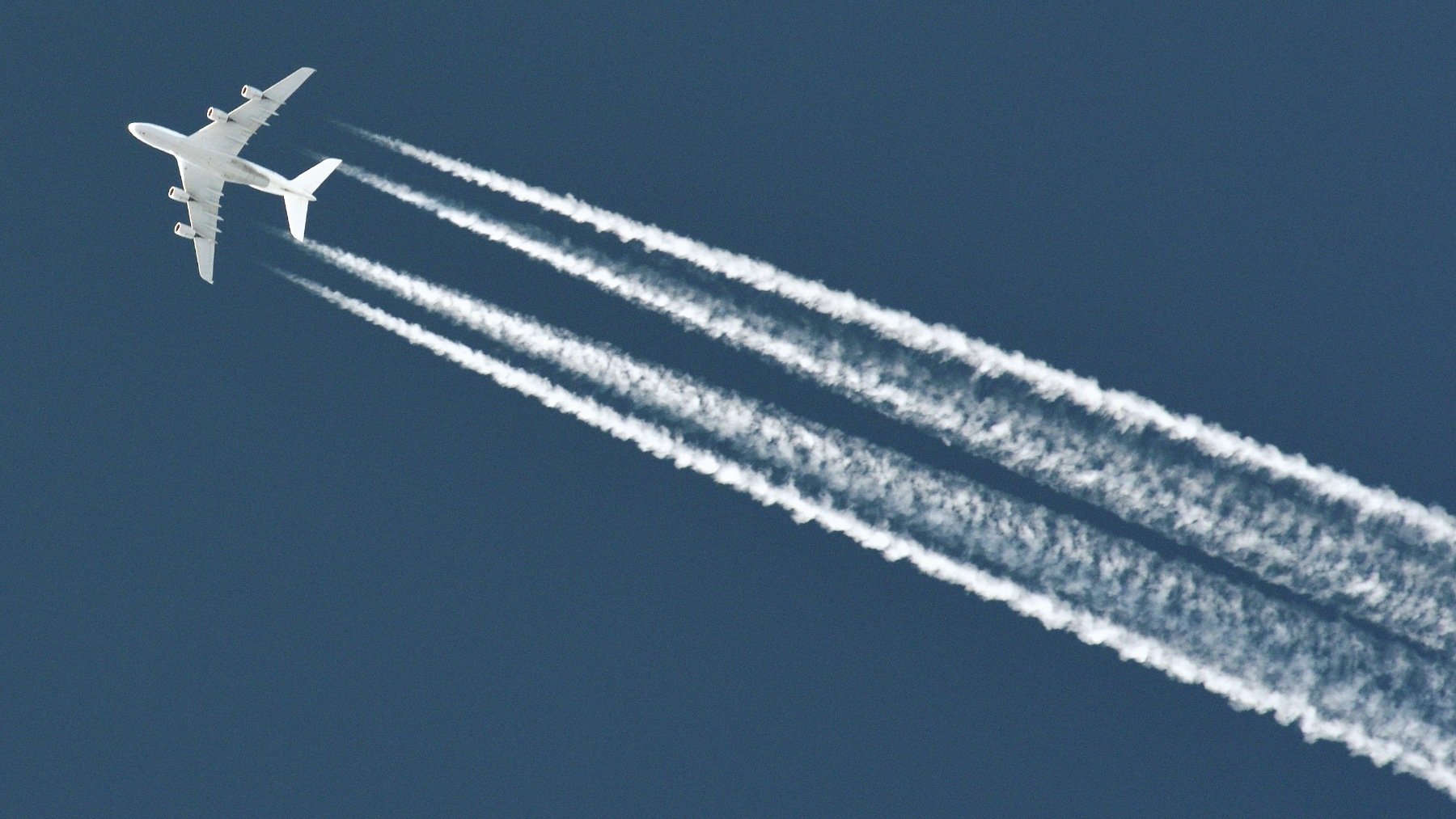 Avión comercial con estelas blancas en el cielo