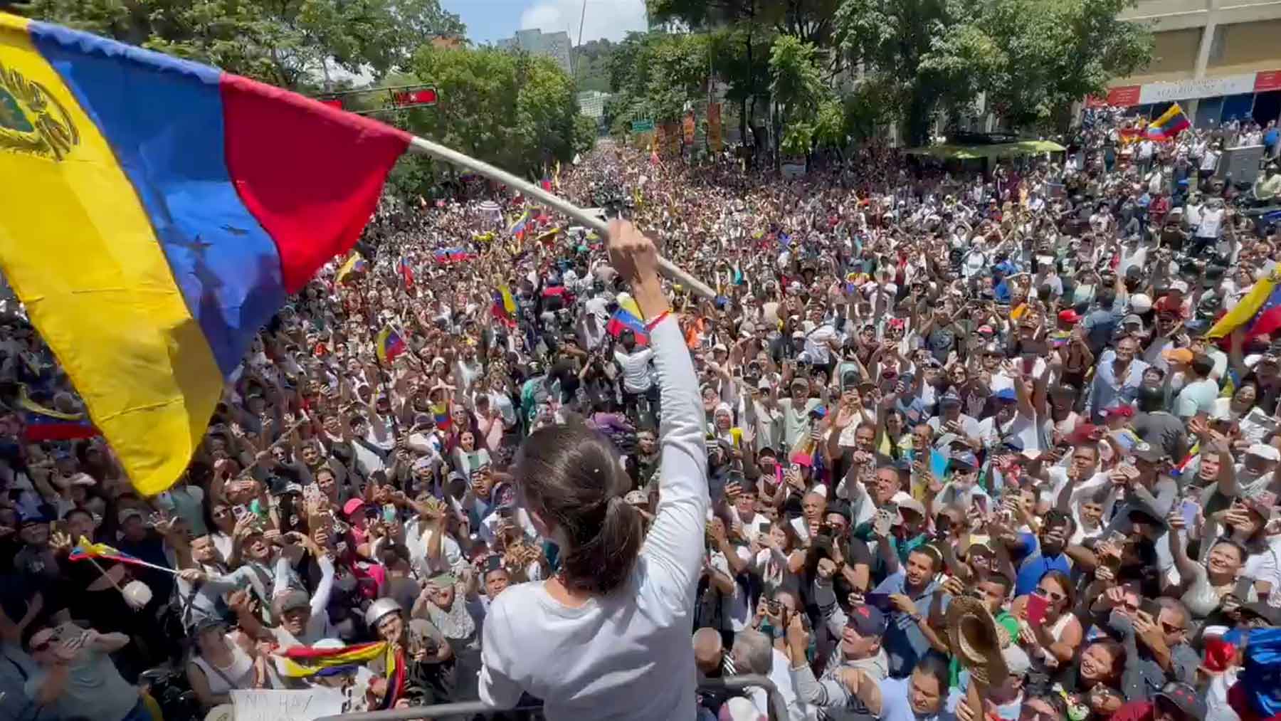 María Corina Machado ondea la bandera de Venezuela ante cientos de miles de manifestantes.