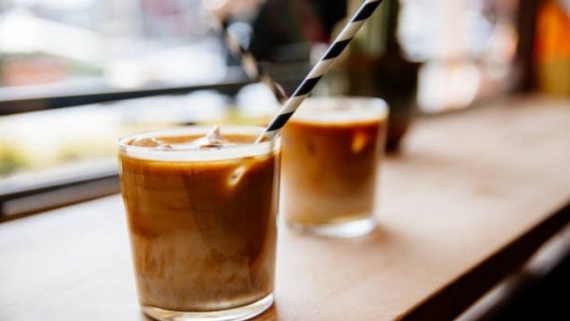 Foto de dos vasos de café con leche frío con sus pajitas para beber y con hielos.