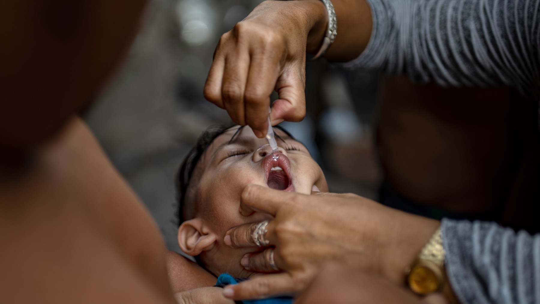 Una persona vacuna a un niño contra la polio.