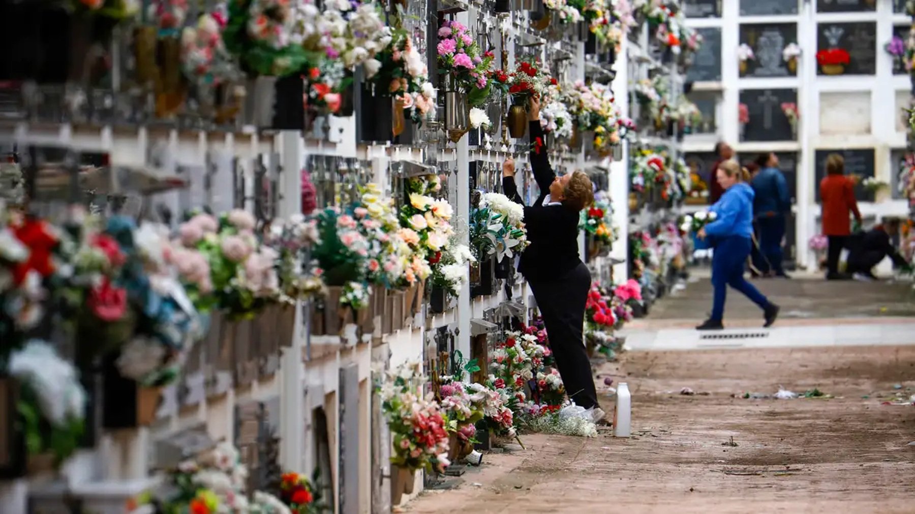 Una persona coloca flores en un cementerio. (Foto: Efe)