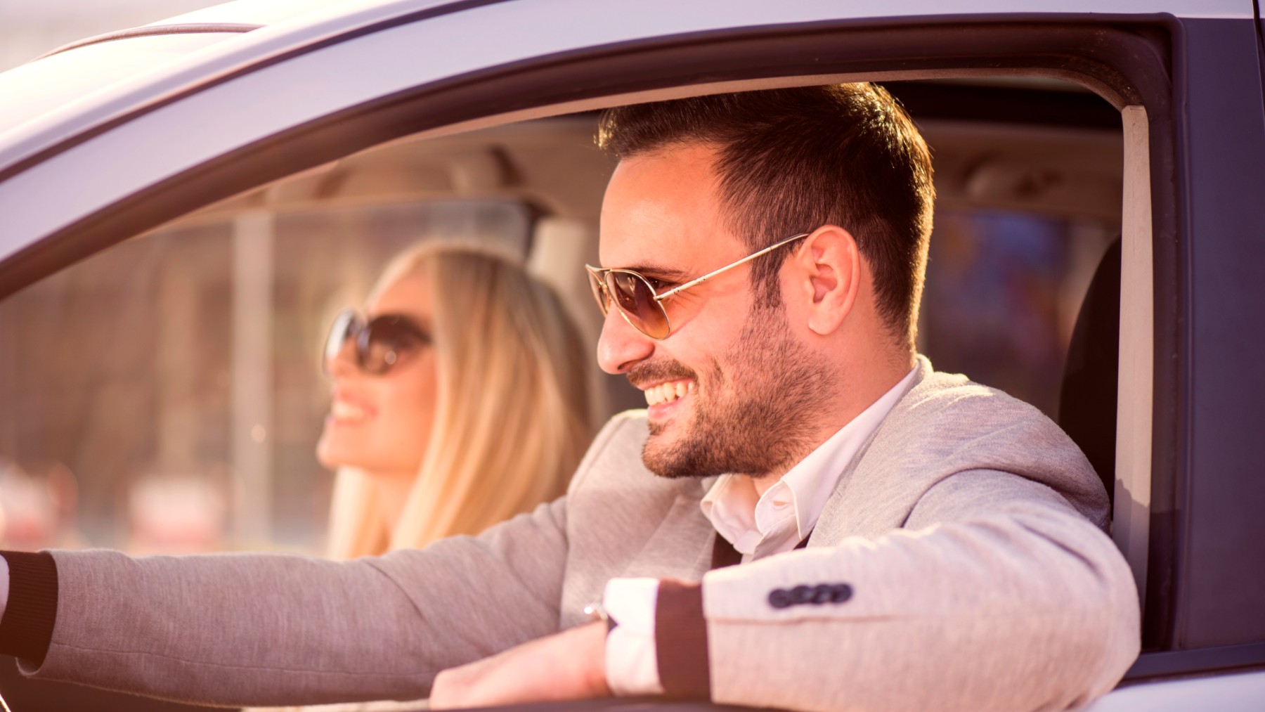 Una pareja viaja en coche con gafas de sol para evitar deslumbramientos del sol.