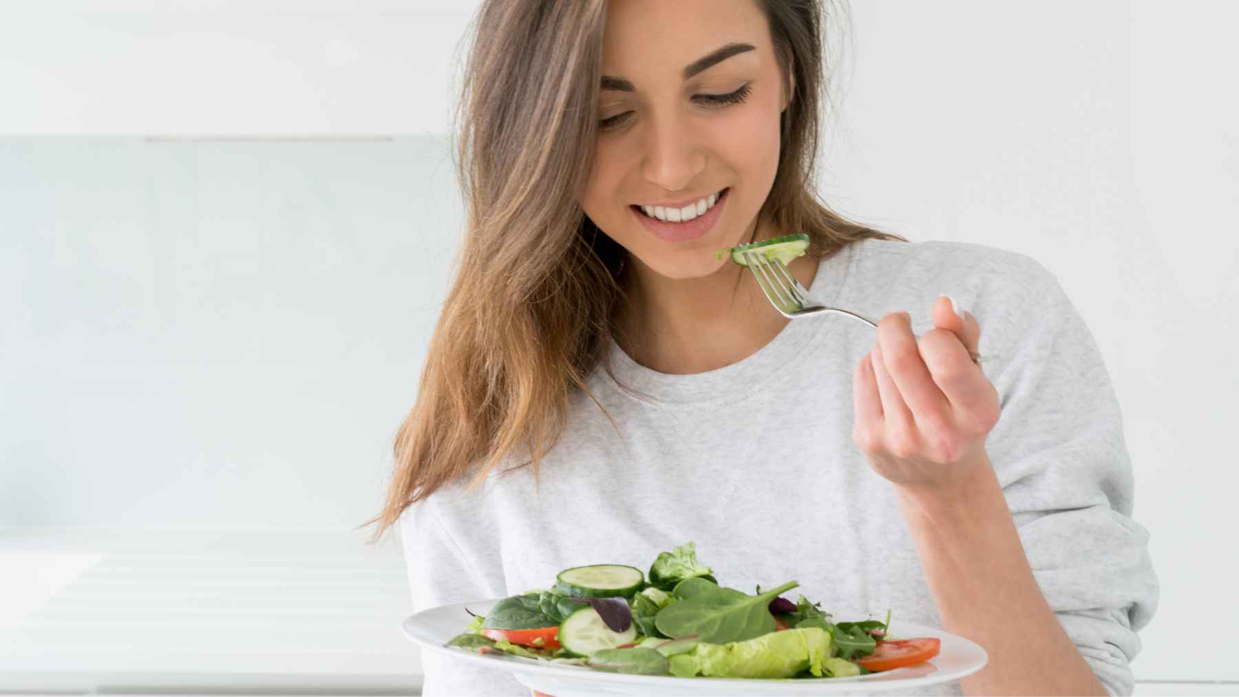 Una mujer comiendo una ensalada.