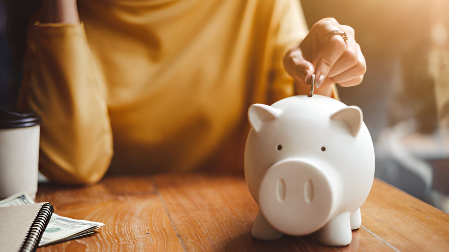 Mujer echando moneda dentro de una hucha.