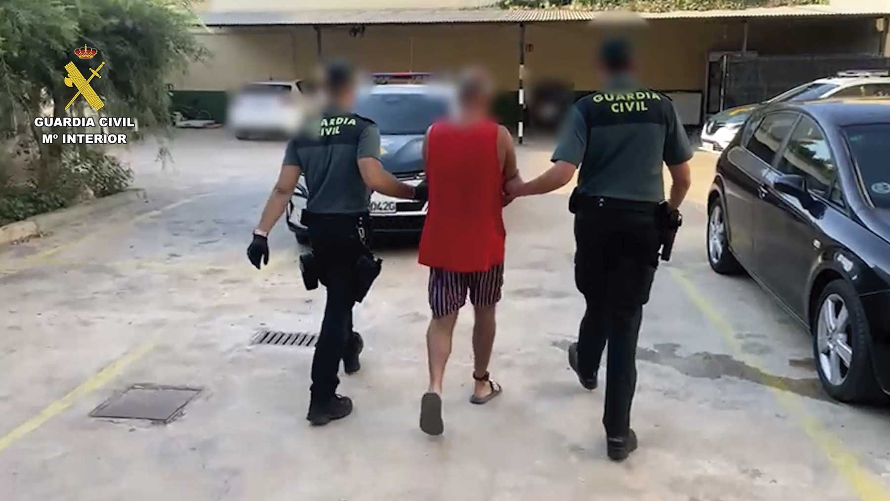 Dos agentes de la Guardia Civil conducen al detenido al vehículo.