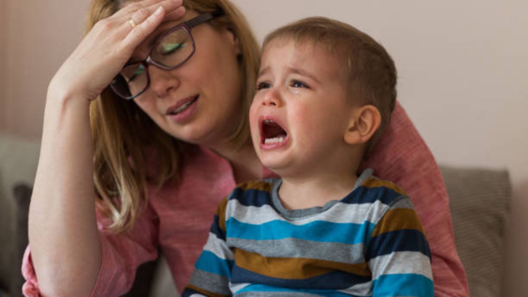 Niño llorando y su madre cansada.