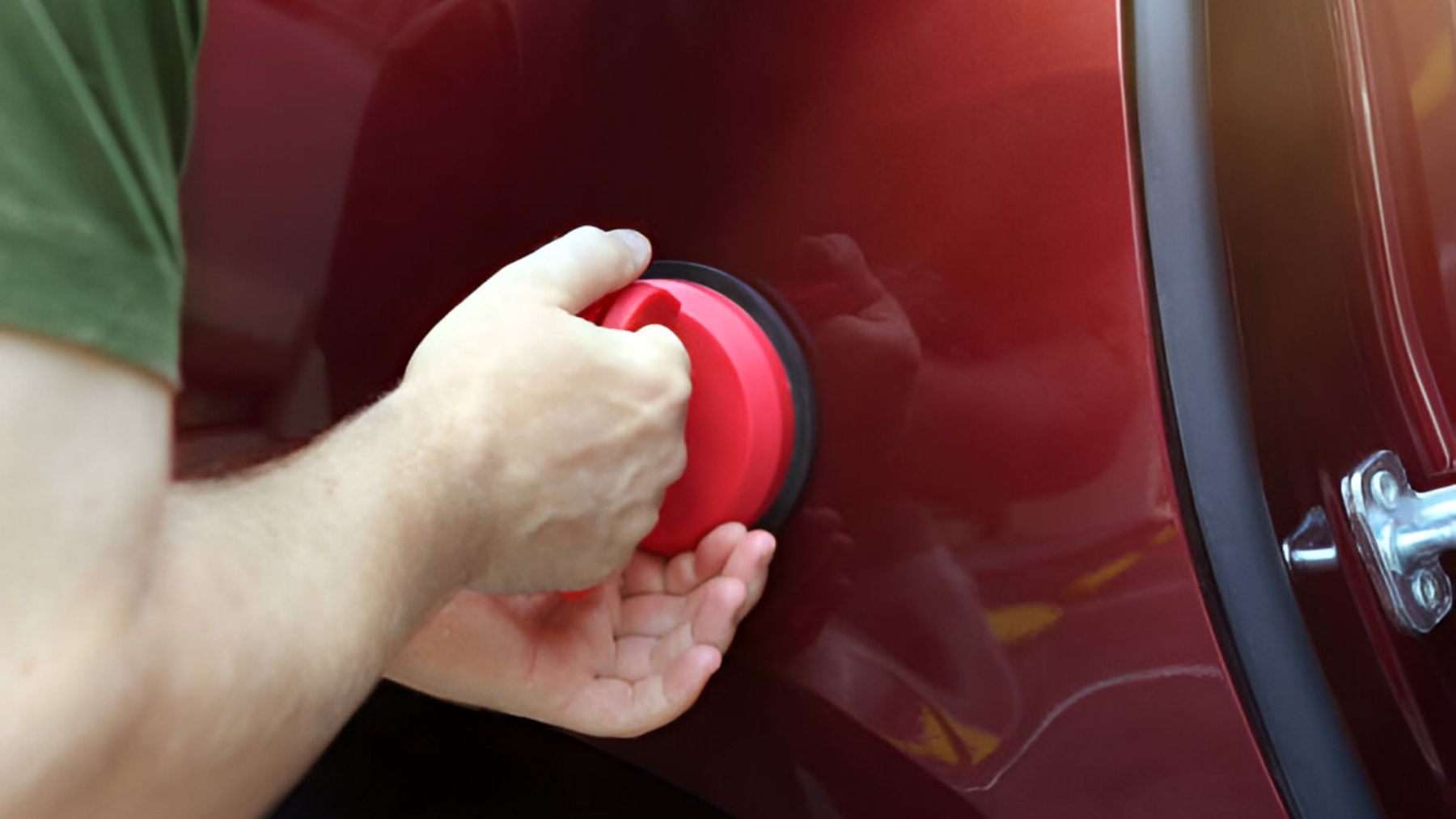 Hombre reparando abolladura del coche con una ventosa.