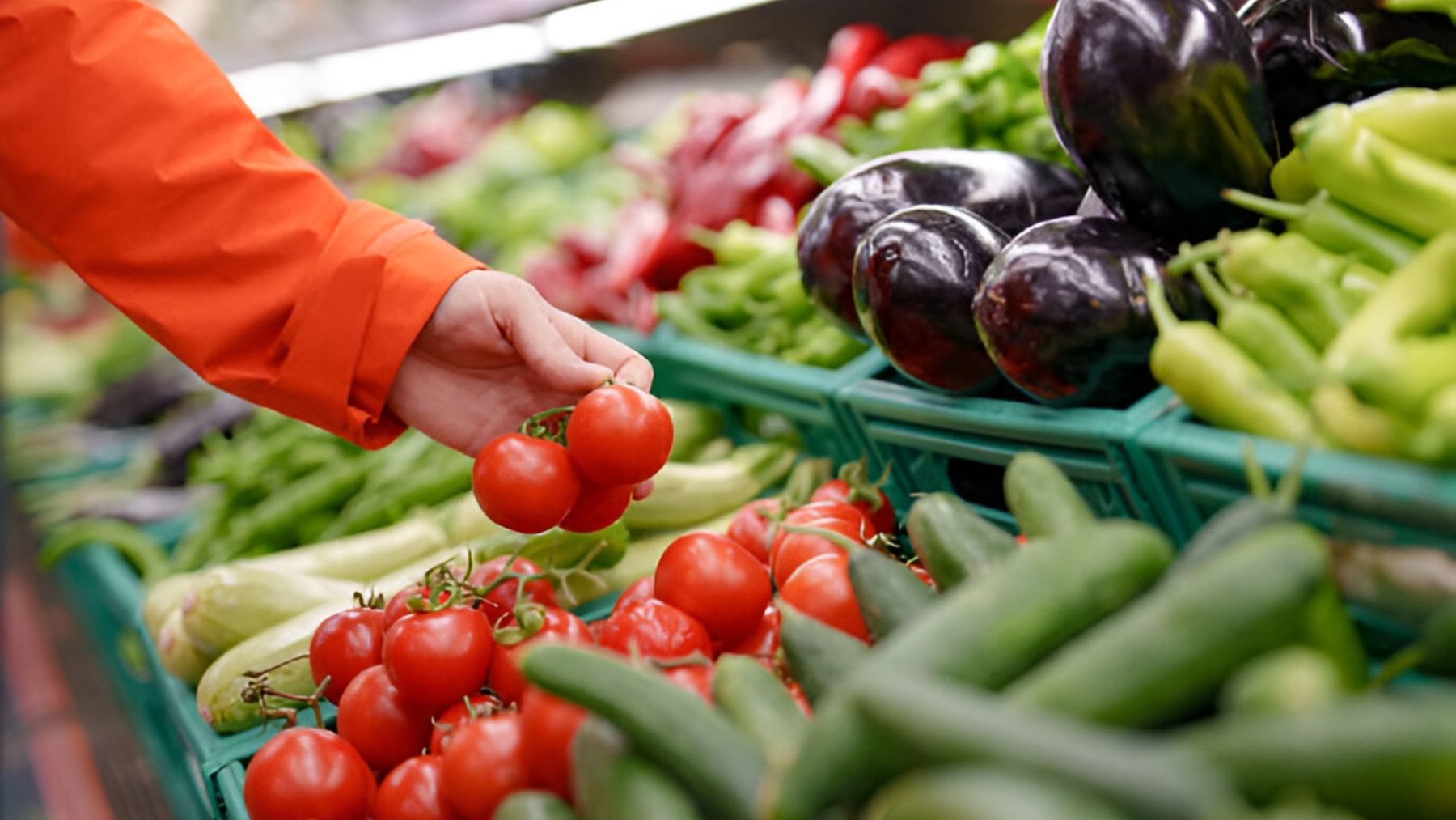 Mujer cogiendo tomates en una tienda.