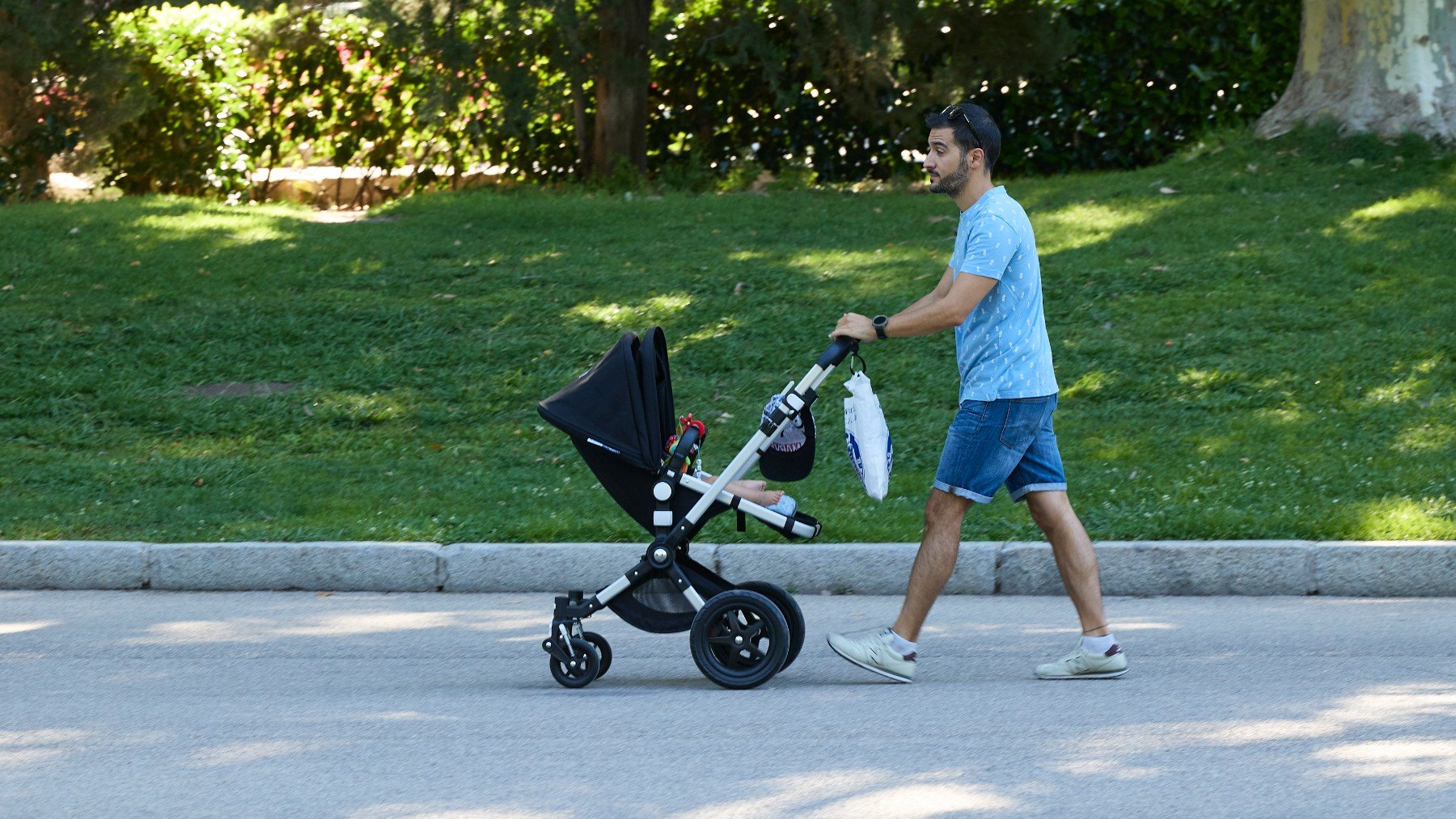 Una padre pasea a su hijo por un parque en Madrid. (EP