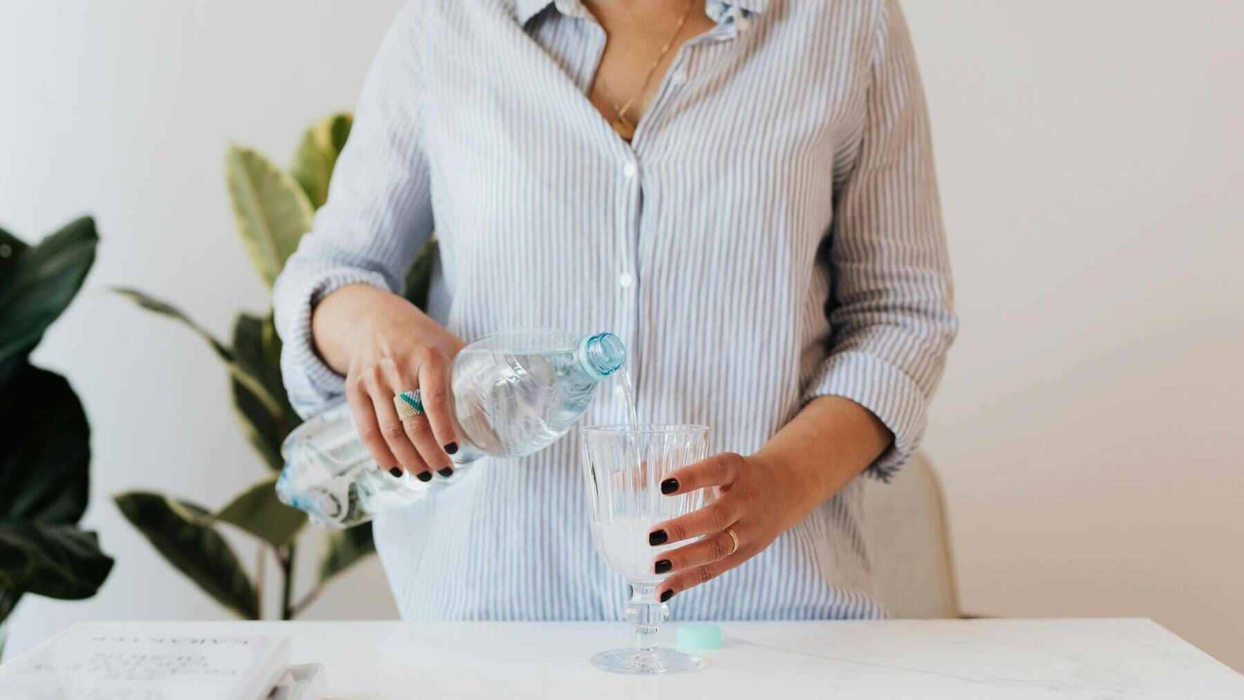 Mujer rellena un vaso de agua.