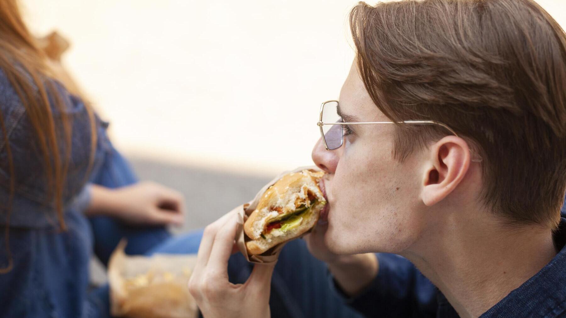 Un hombre muerde su bocadillo.