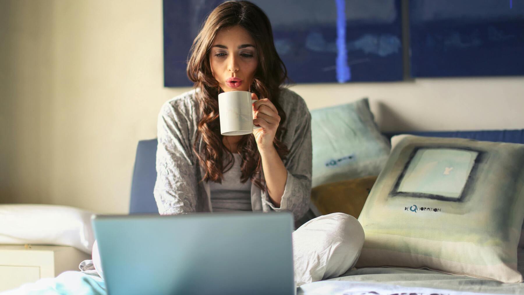 Mujer con una taza de café en la cama.