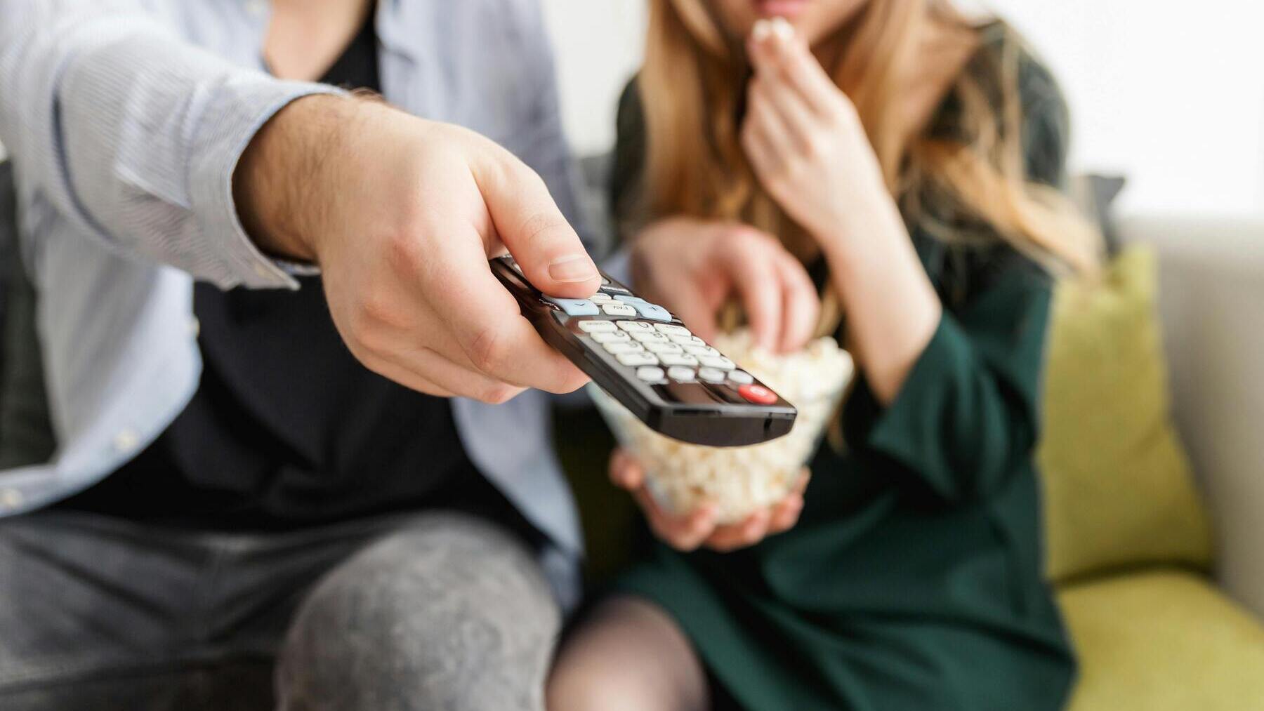 Pareja come palomitas y utiliza el mando de la televisión.