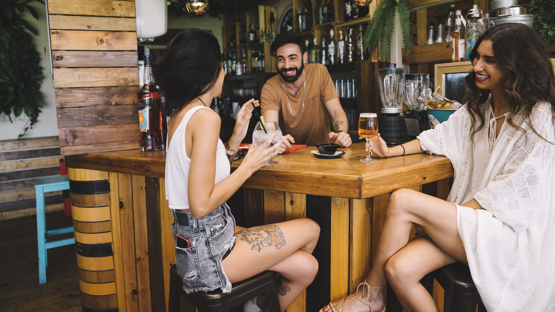 Tres amigos toman cerveza en un bar. Foto: Freepik.