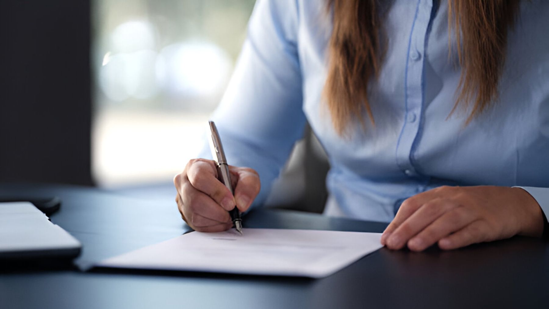 Mujer firmando documento.