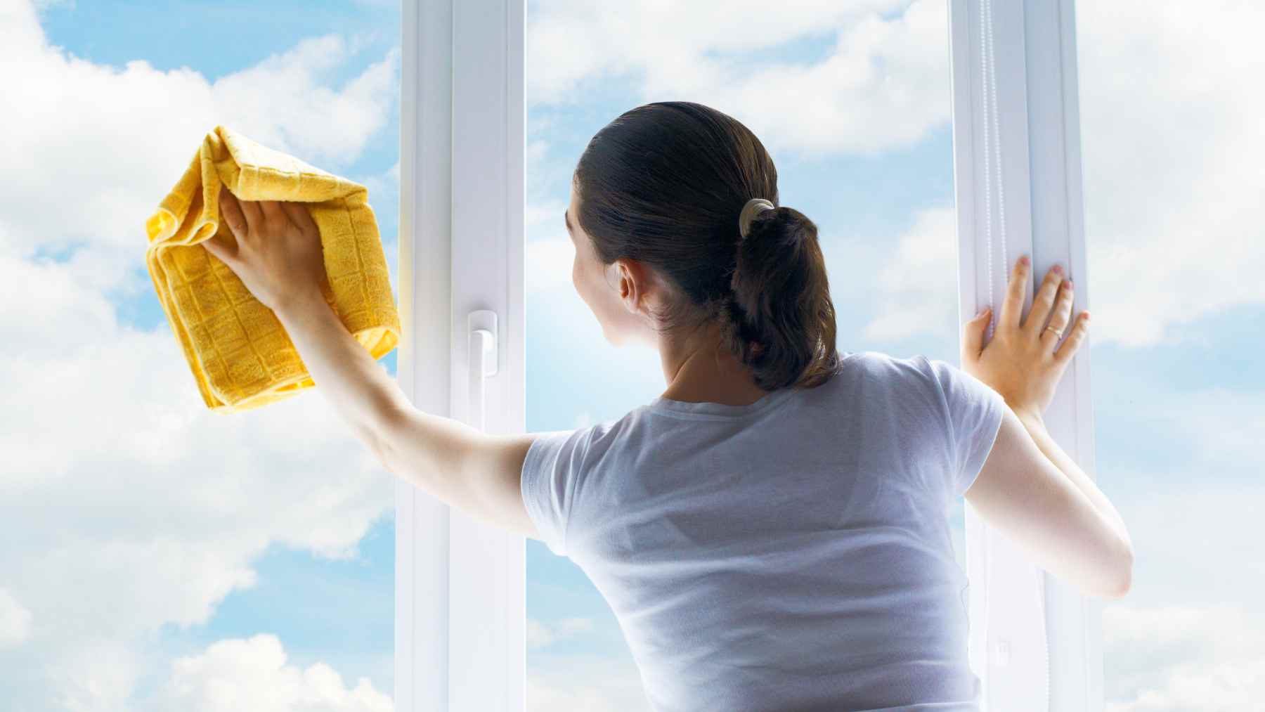 Una joven limpiando las ventanas.