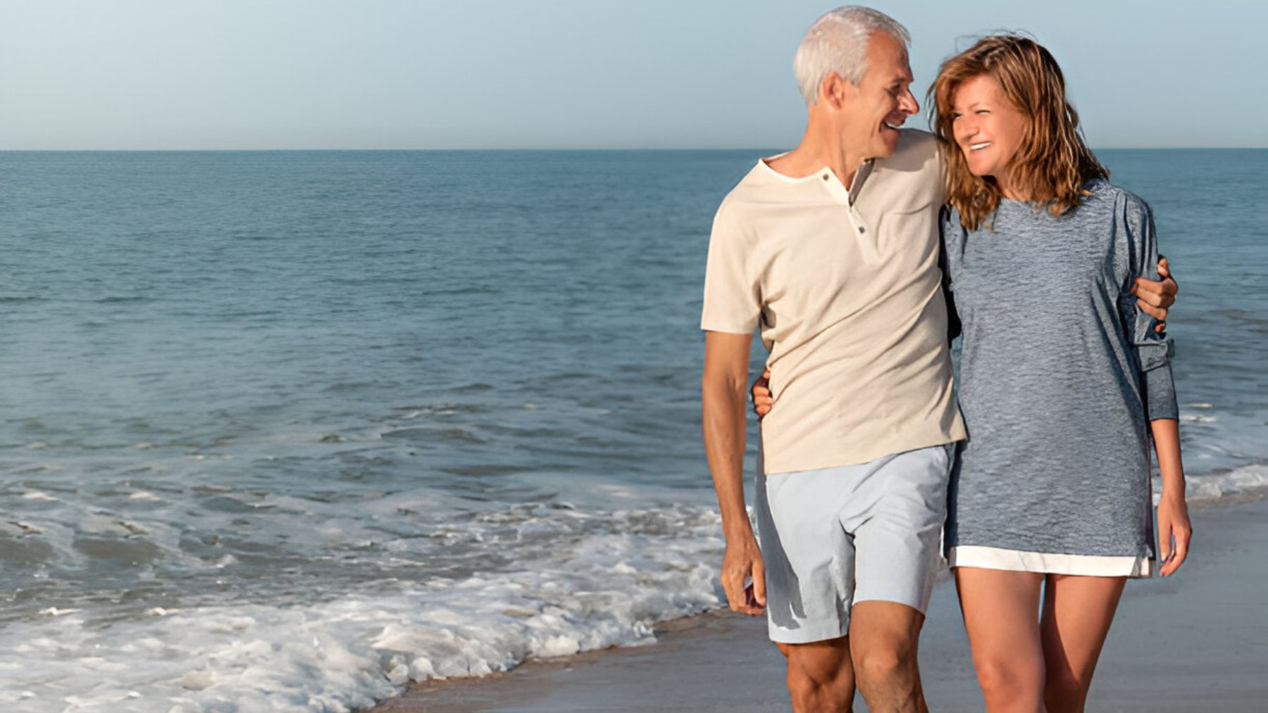 Pareja caminando por la orilla de la playa.