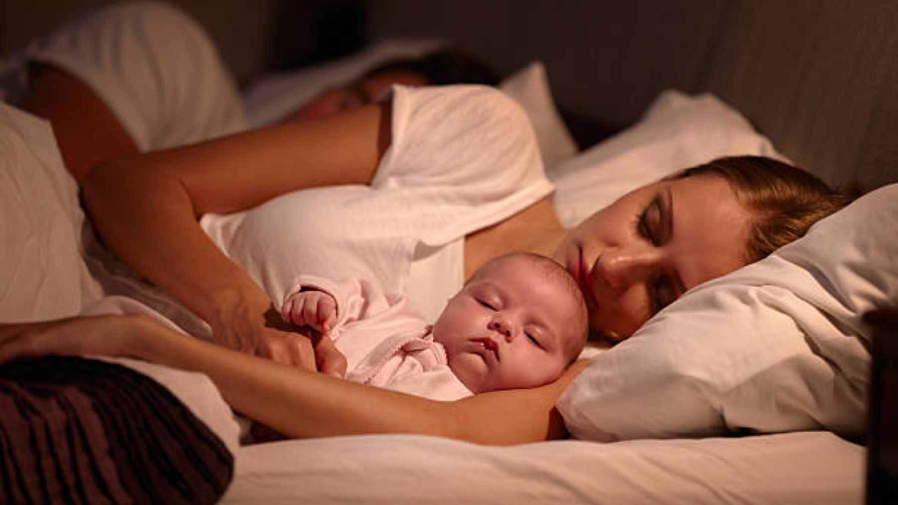 Padres durmiendo con el bebé.