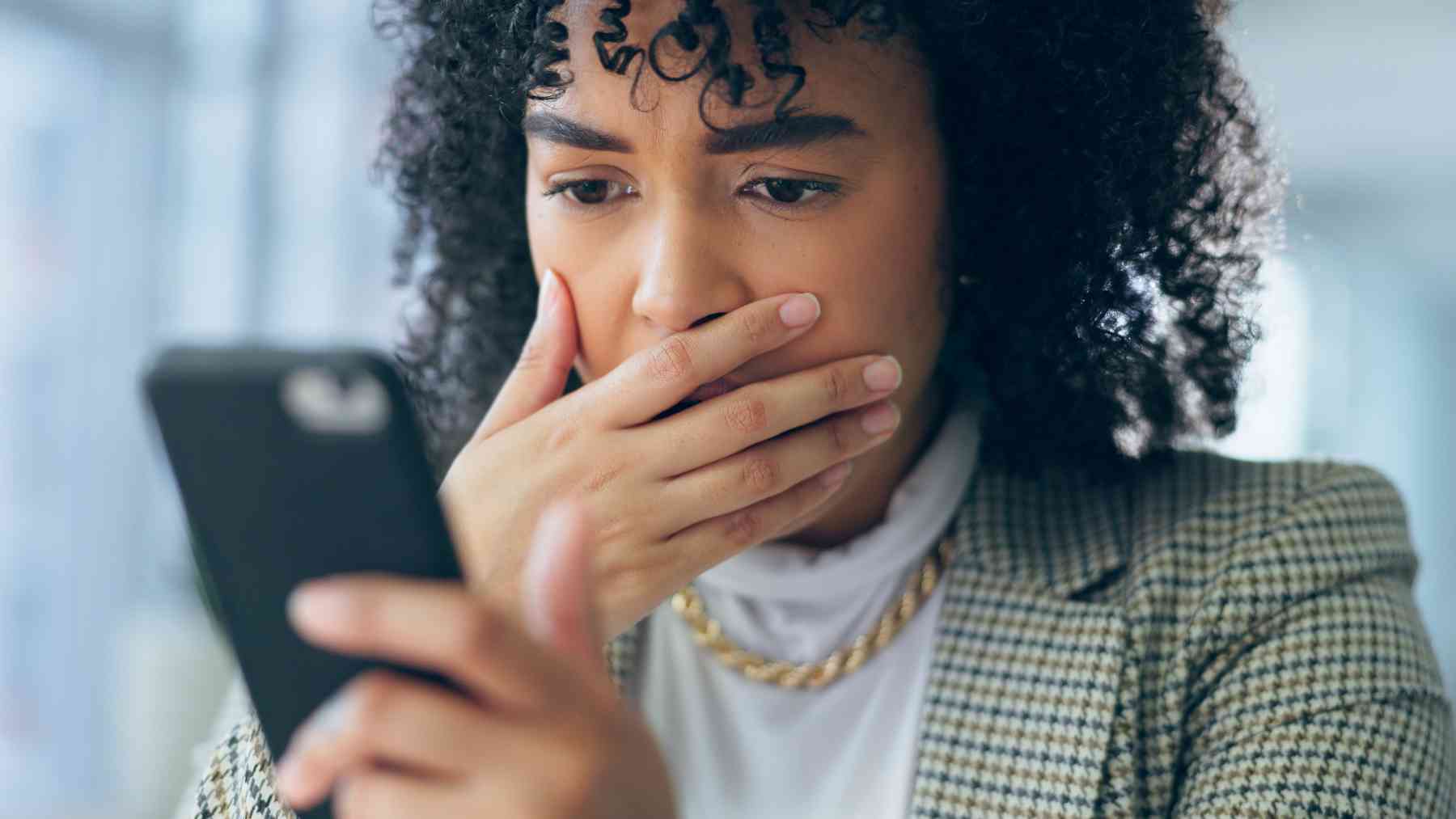 Una mujer sorprendida mirando su teléfono.