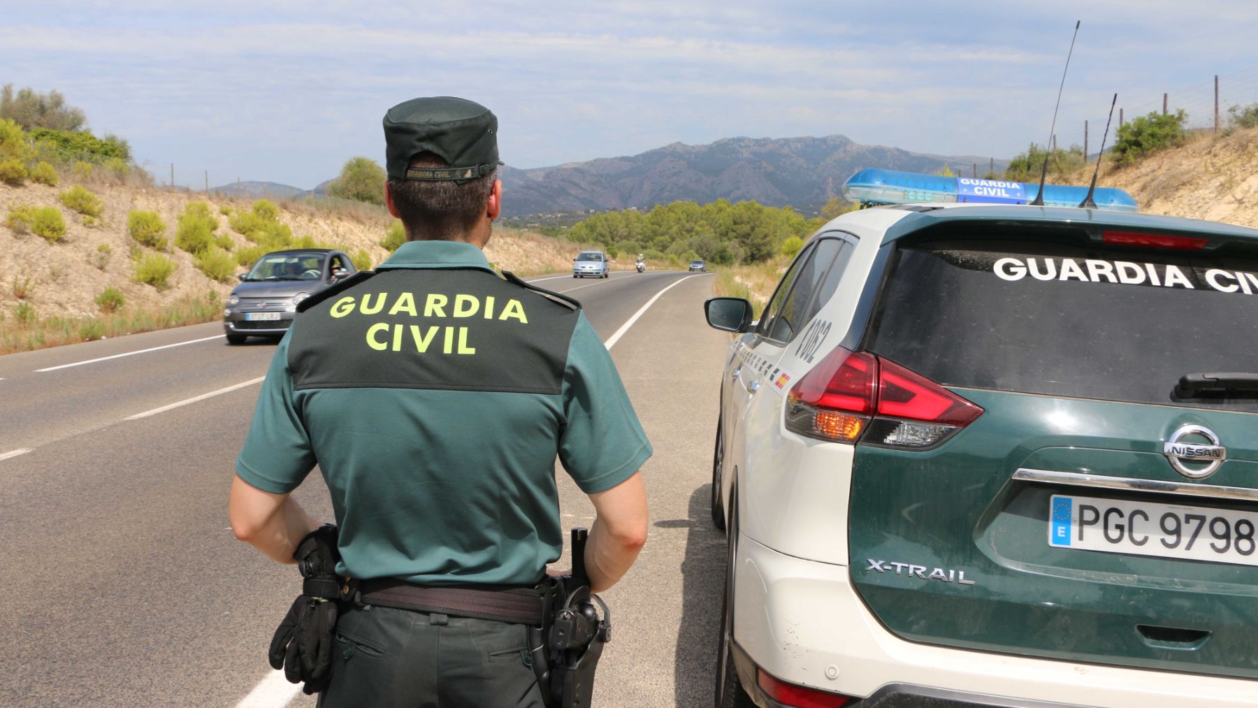 Un agente de la Guardia Civil junto a su vehículo.