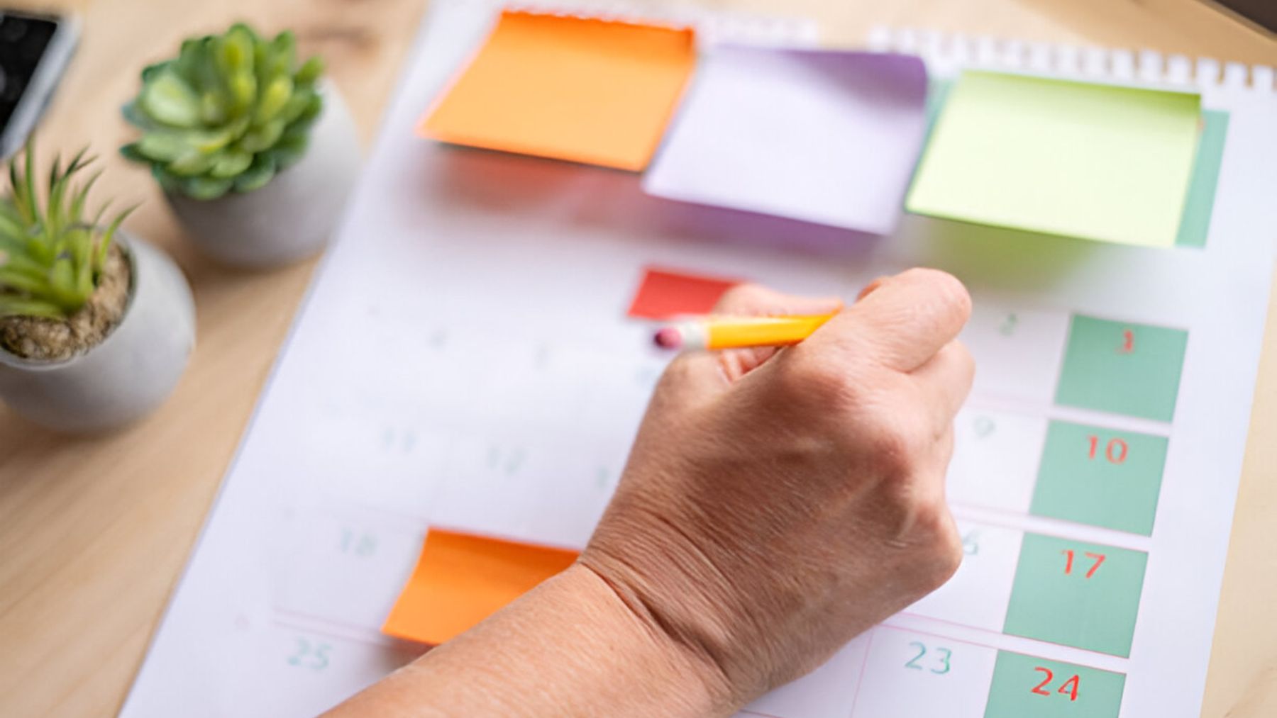 Mano escribiendo en un calendario.