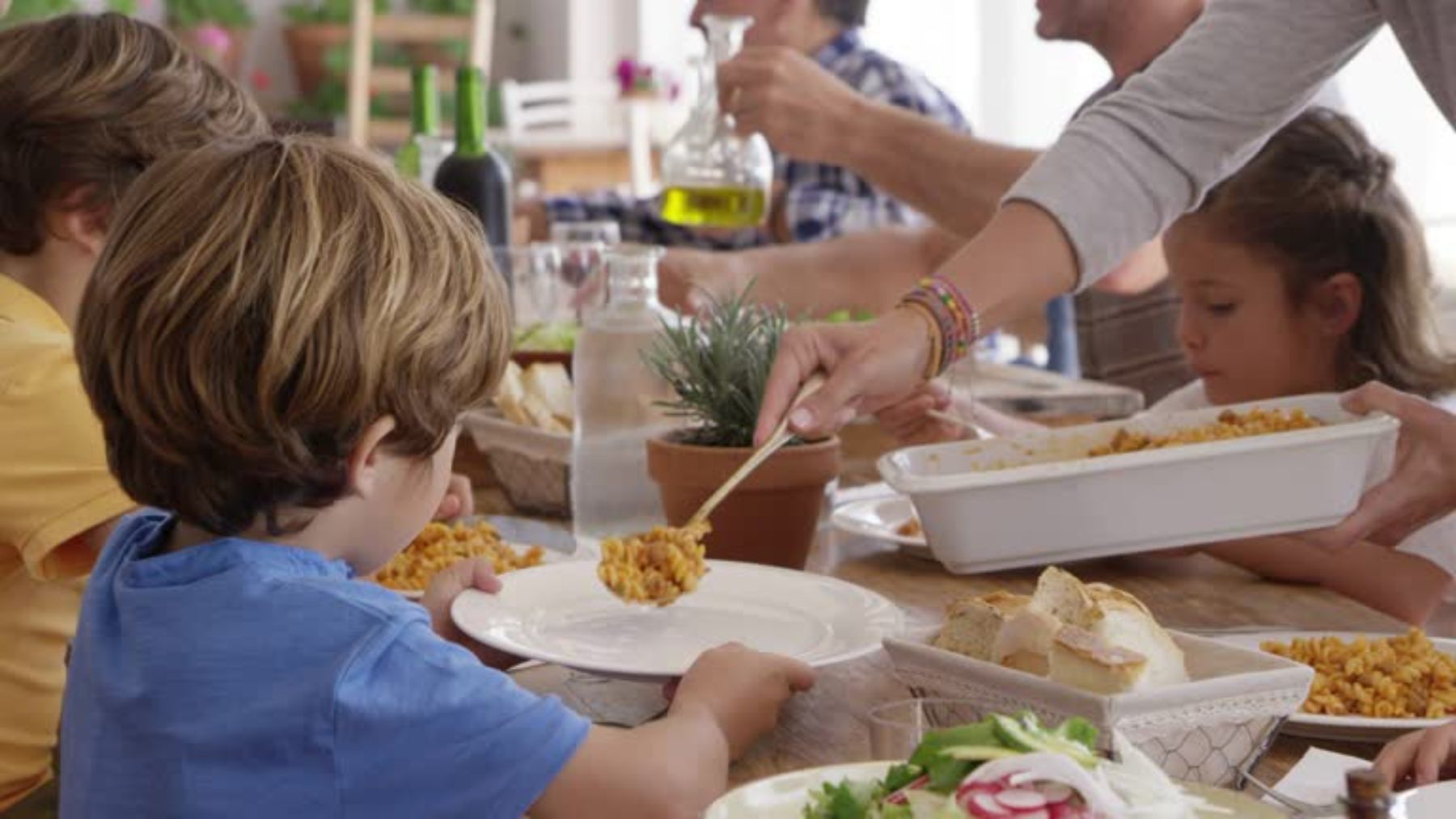 Madre sirviendo comida a un niño en su plato.