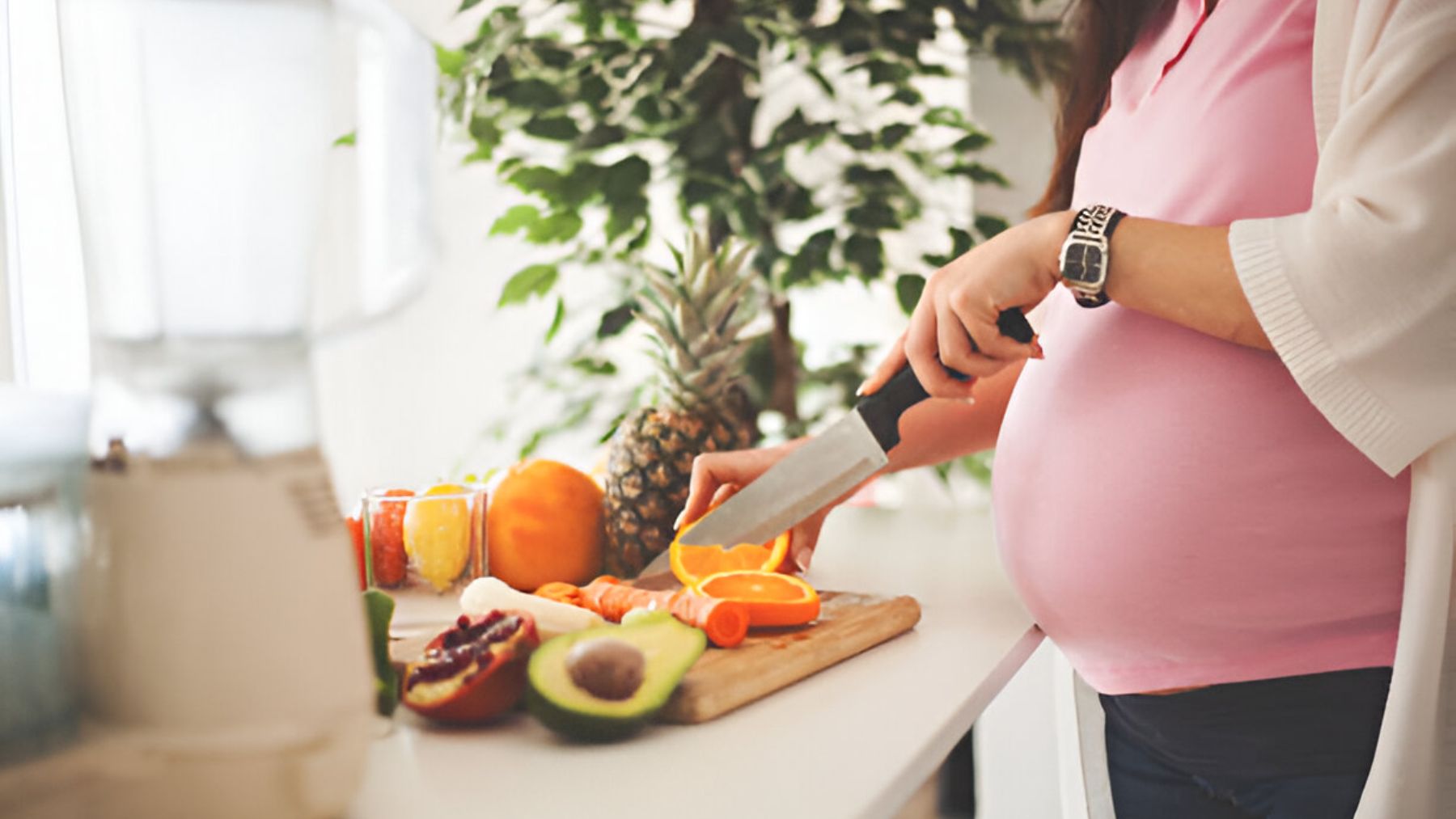 Mujer embarazada cortando fruta.