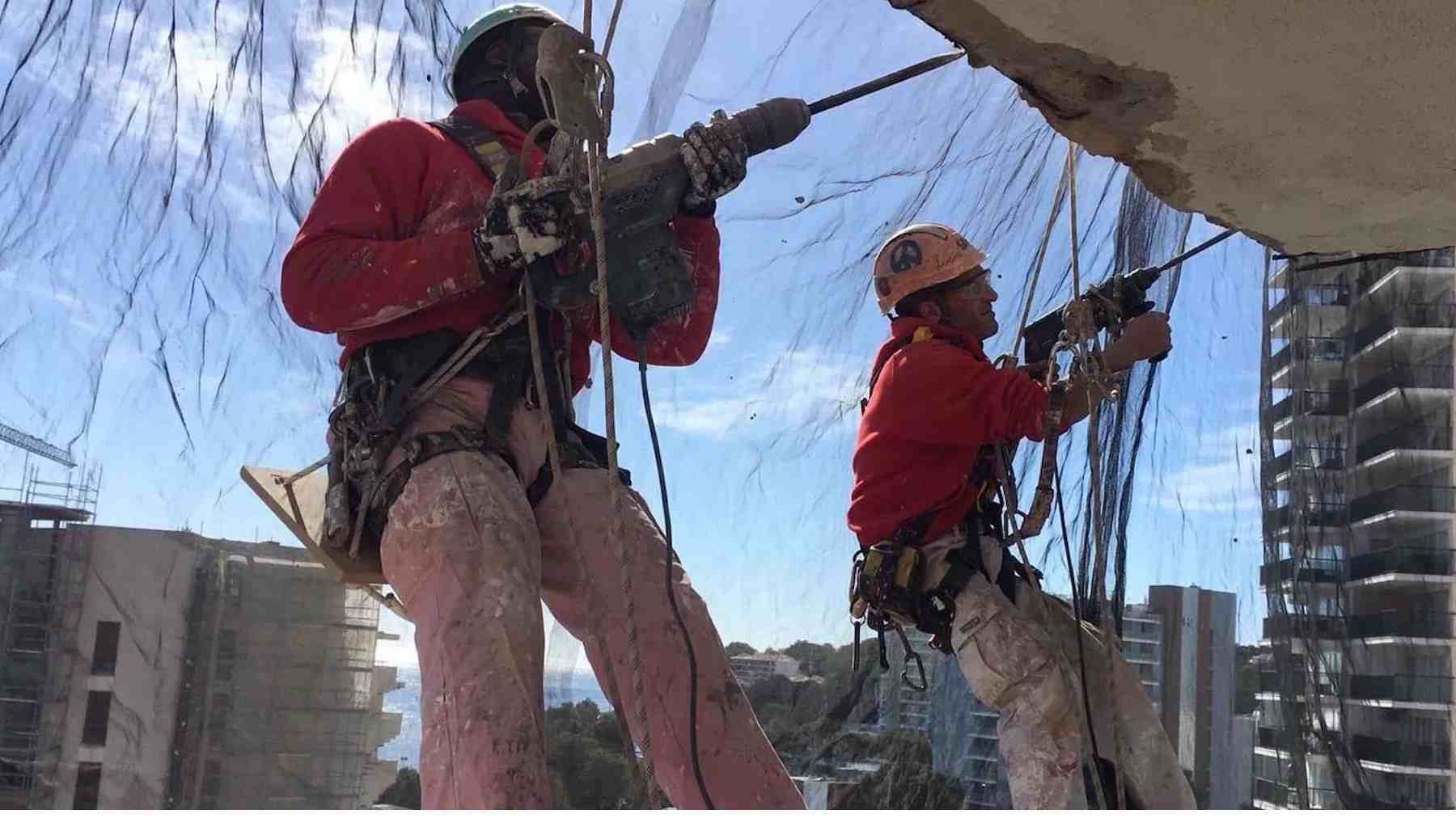 Dos operarios trabajan en labores de mantenimiento de un edificio.