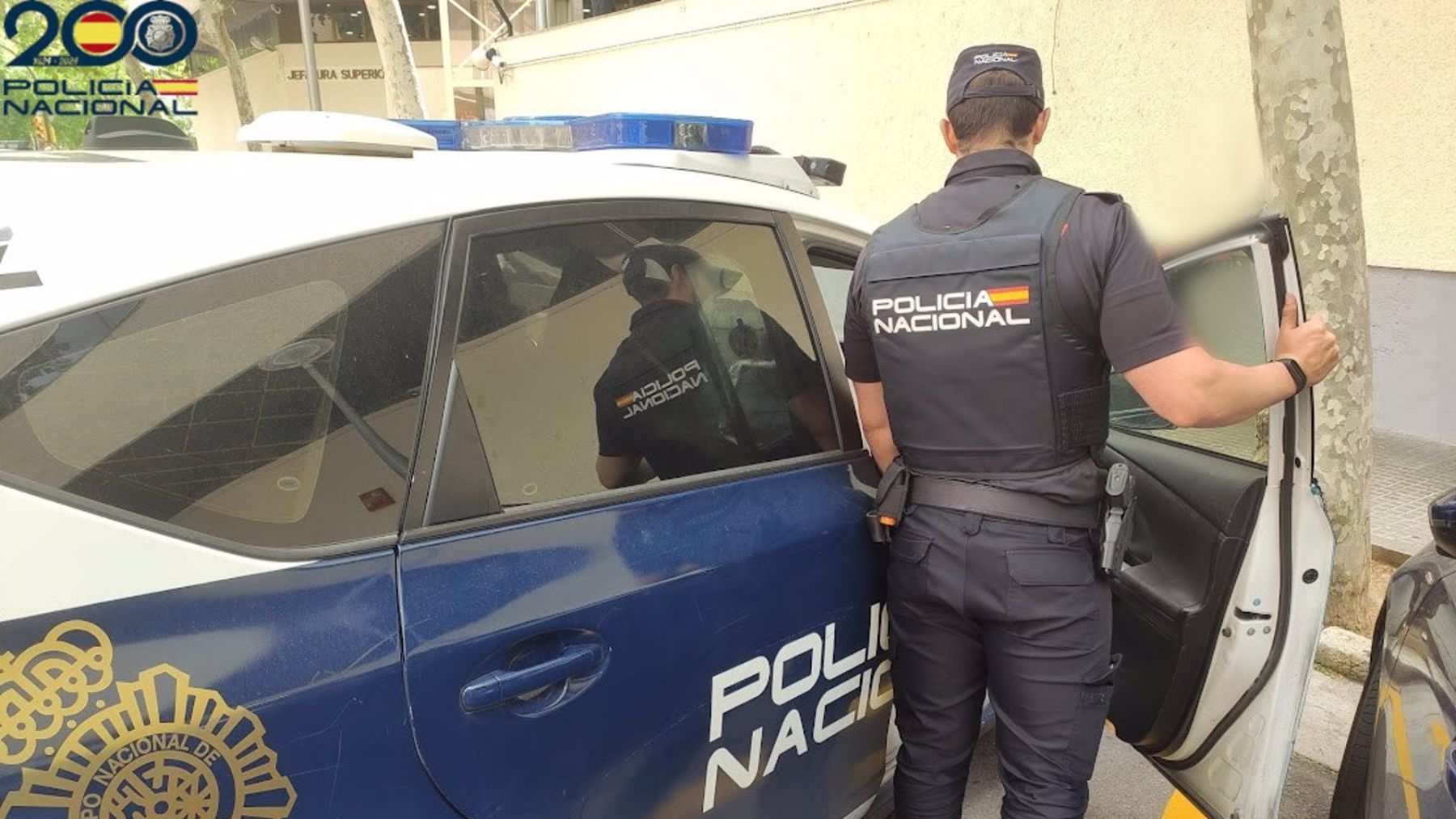 Un agente de Policía Nacional, junto a su vehículo.