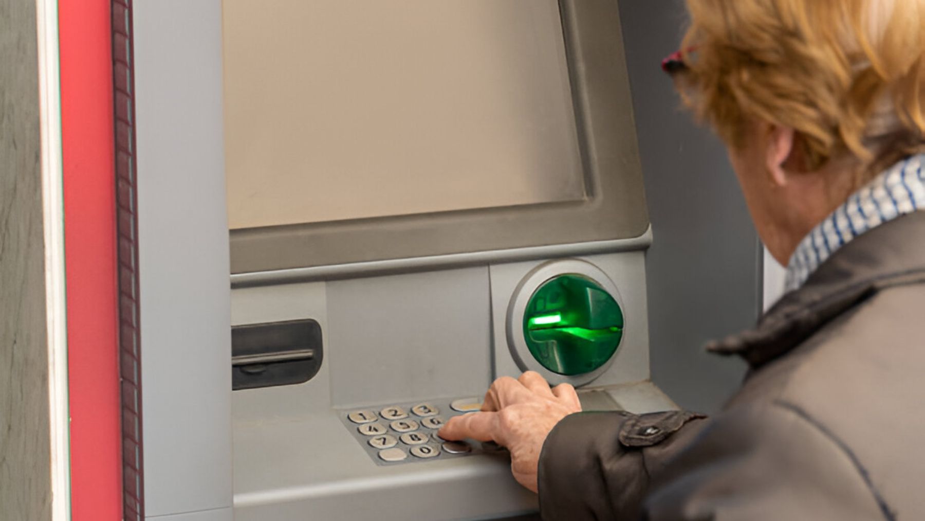 Mujer mayor sacando dinero de un cajero.