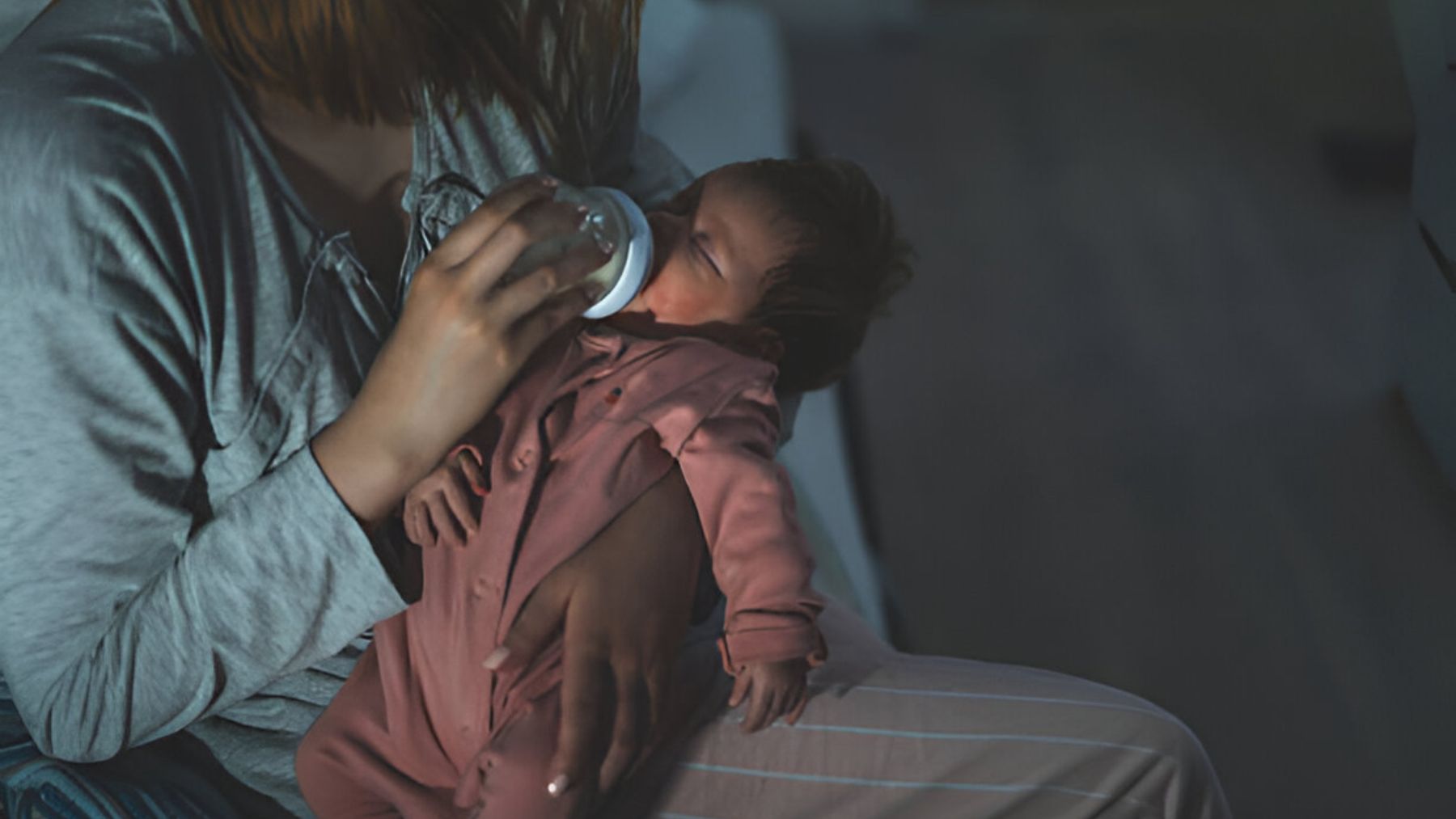 Madre alimentando su bebé por la noche.