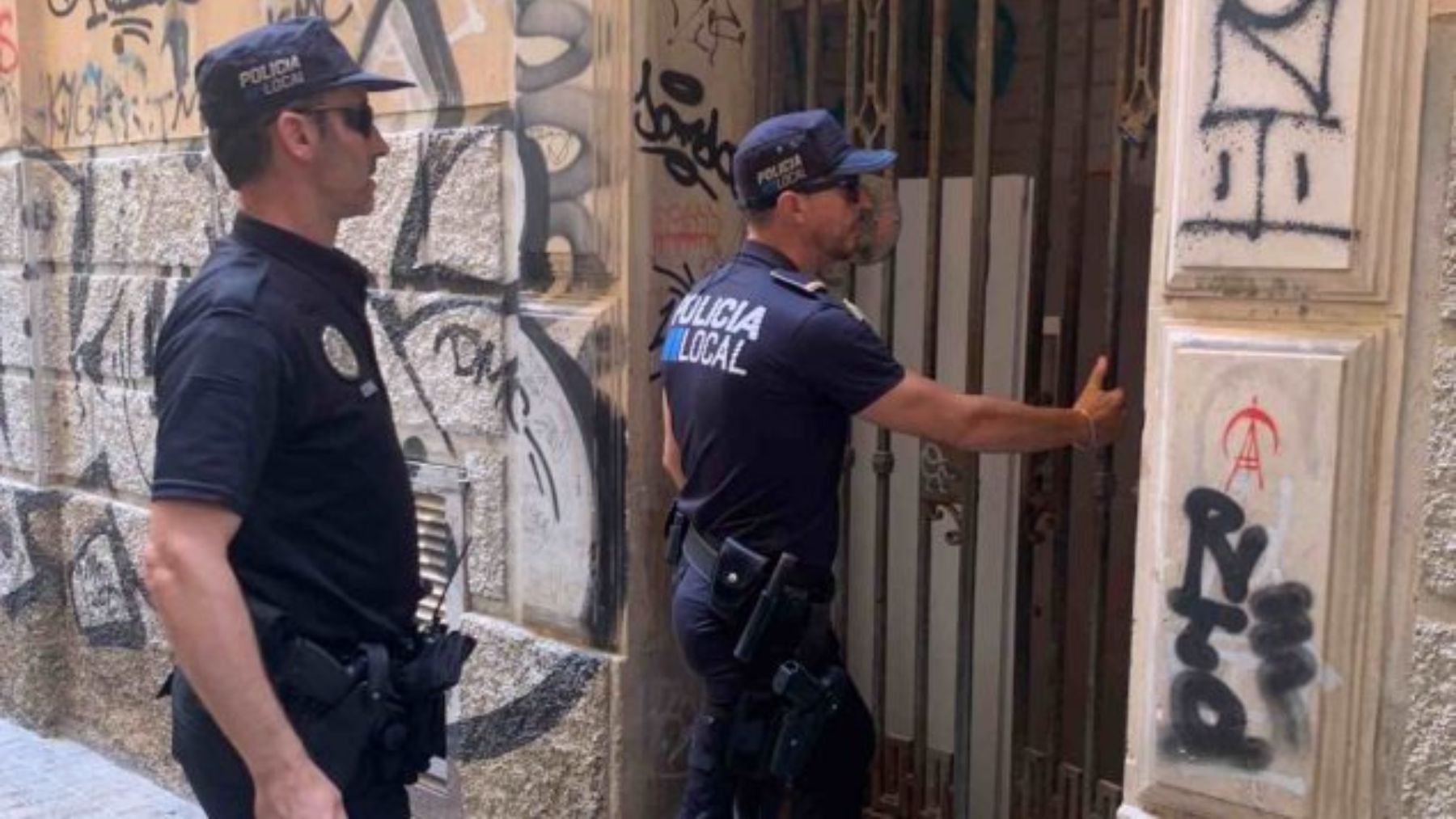 Dos agentes de la Policía Local en el desalojo de una vivienda okupada.