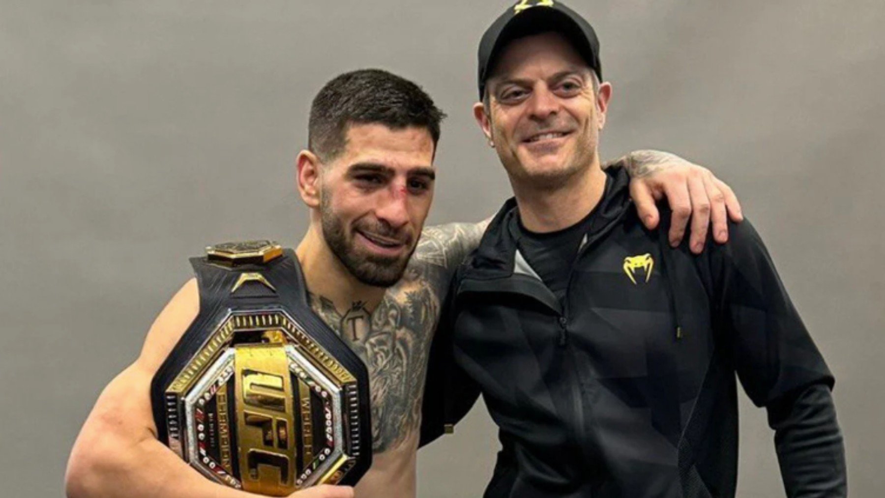 Ilia Topuria posa con el cinturón de campeón de UFC junto a Aldo Martínez, su preparador físico. (UFC)